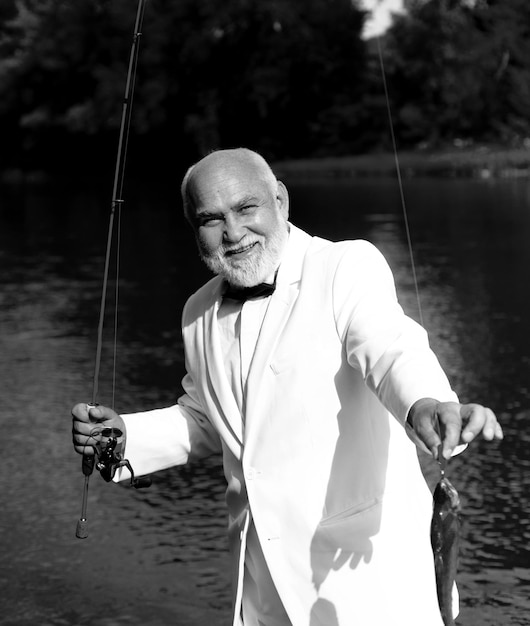 Starszy mężczyzna łowiący eleganckiego brodatego mężczyznę z rybami letnie wakacje letnie weekendy lub wakacyjne wędkowanie