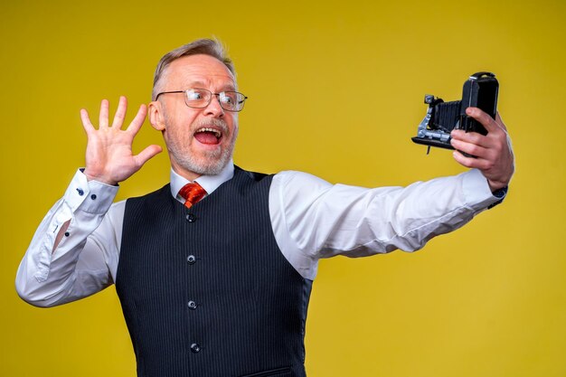 Starszy mężczyzna patrząc na kamery podczas robienia selfie głupią minę macha do aparatu