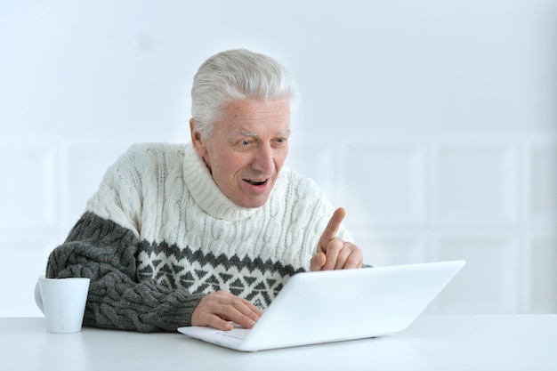 Starszy mężczyzna pracujący w biurze, korzystający z laptopa