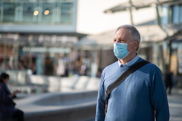 Starszy mężczyzna spacerujący na świeżym powietrzu, mając na sobie maskę ochronną przeciwko koronawirusowi