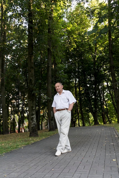 Starszy mężczyzna spaceruje samotnie po parku latem Portret starego mężczyzny, który jest sam w parku wśród drzew