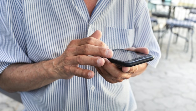 Starszy Mężczyzna Trzyma W Rękach Telefon Komórkowy