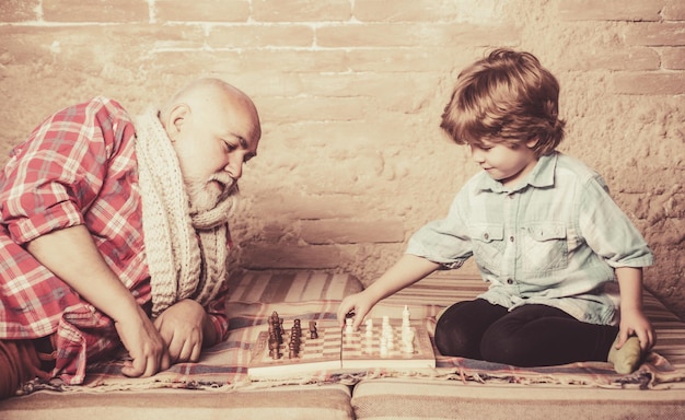 Starszy mężczyzna uczy swojego wnuka grać w szachy przystojny dziadek i wnuk grają w szachy, podczas gdy