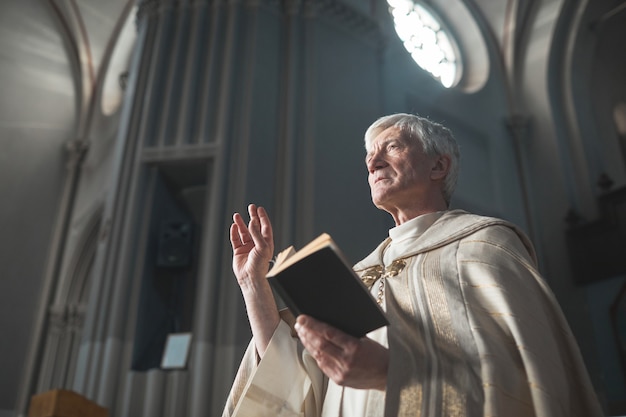 Starszy mężczyzna w kostiumie czyta Biblię podczas służby w kościele