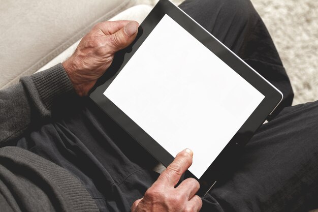 Starszy mężczyzna w swetrze używający tabletu