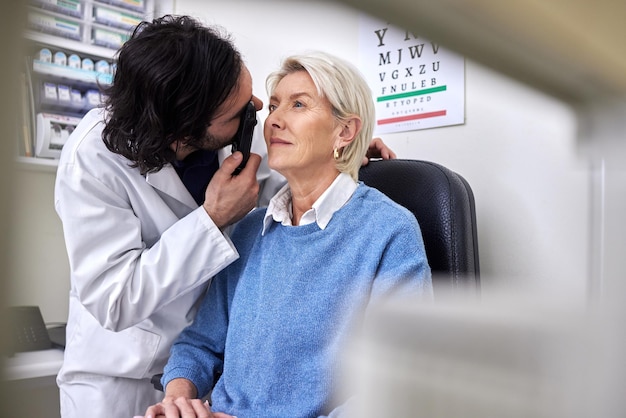 Starszy pacjent w badaniu wzroku lub badaniu wzroku przez lekarza optometrystę lub okulistę z pomocą medyczną Dojrzała kobieta lub klient z pomocnym optykiem, aby zobaczyć siatkówkę lub sprawdzić jaskrę