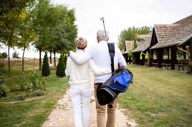 Zdjęcie starszy para trzymając się razem i ciesząc się rekreacyjnym czasem na emeryturze, grając w golfa.