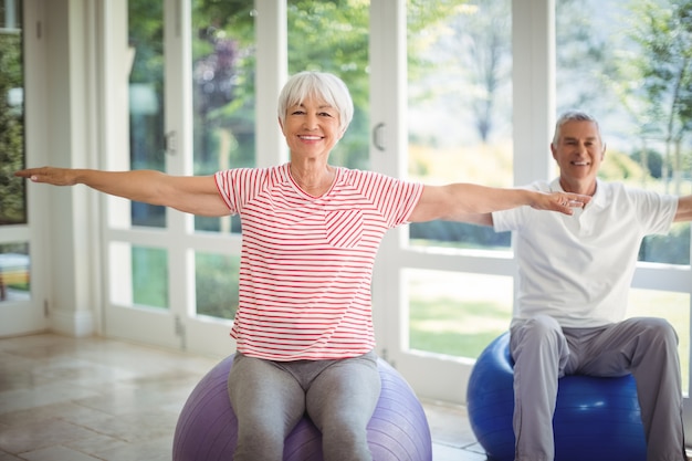 Starszy para wykonywania ćwiczeń rozciągających na piłce fitness