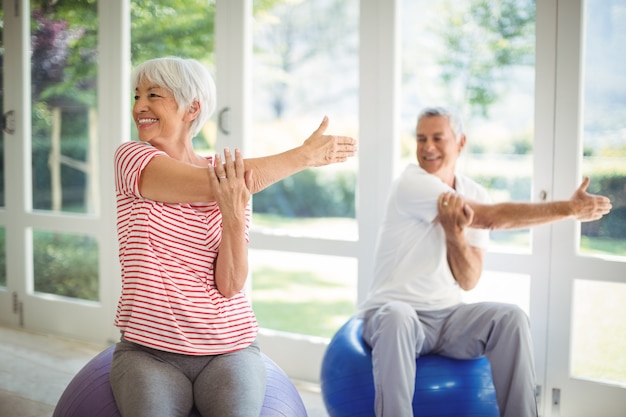 Starszy para wykonywania ćwiczeń rozciągających na piłce fitness