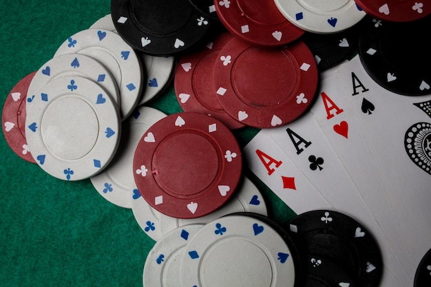 Starszy poker. Cztery karty do gry, cztery asy i żetony do pokera na zielonym stole w kasynie.