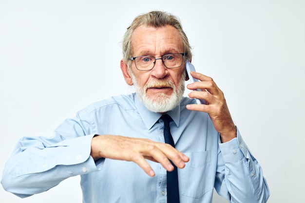 Starszy siwy mężczyzna w koszuli z krawatem rozmawia przez telefon przycięty widok