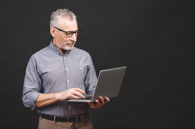 Starszy starzejący się brodaty stary człowiek trzyma laptop i ono uśmiecha się w eyeglasses