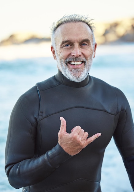 Starszy surfer i plaża ze znakiem ręki do portretu z uśmiechem latem nad oceanem dla dobrego samopoczucia, sprawności i zdrowia Starszy mężczyzna i surfowanie drogą morską na emeryturze na wakacjach lub podróży do miami