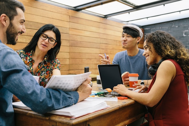 Startup Czterech Wieloetnicznych Osób Radośnie Dyskutujących O Pomysłach W Nowoczesnej Przestrzeni Coworkingowej