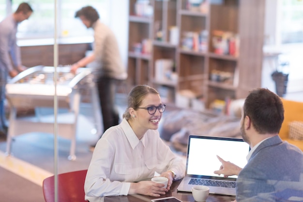 startupowcy korzystający z laptopa przygotowujący się do kolejnego spotkania przy kawie i omawiający pomysły w kreatywnym biurze