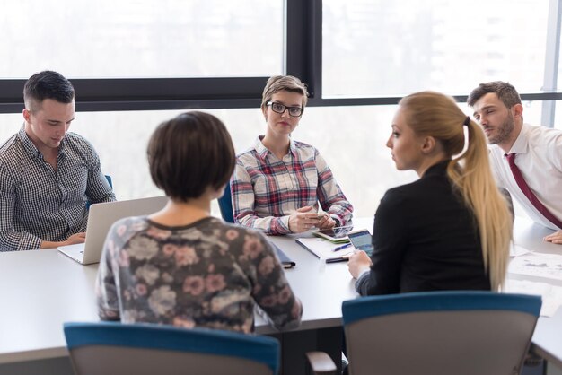 startupowy biznes, młodzi kreatywni ludzie grupują się w burzę mózgów podczas spotkania we wnętrzu biura i używają laptopa i tabletu do notowania pomysłów, planów i projektów