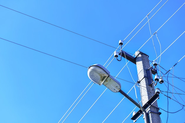 Stary betonowy elektryczny słup dla przekazu depeszował elektryczność z latarnią na tle chmurny niebieskie niebo. Przestarzało mnie. Thod dostarczania energii elektrycznej