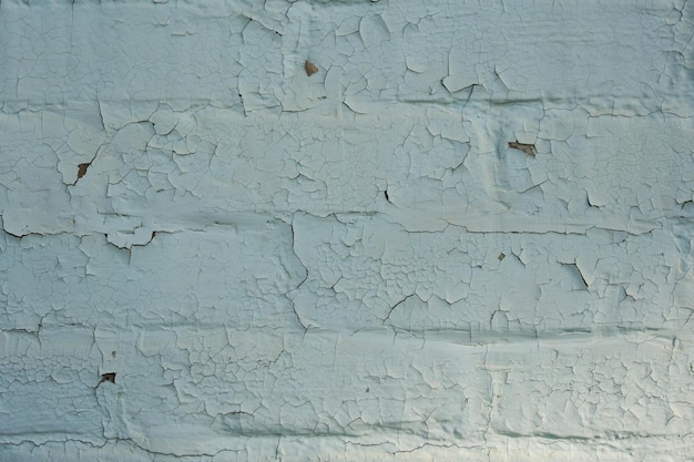 stary ceglany mur pomalowany białą farbą pęknięty od czasu