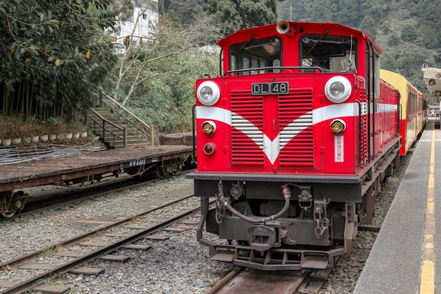 Stary czerwony pociąg linii Alishan wraca na dworzec Chiyi w mglisty dzień.