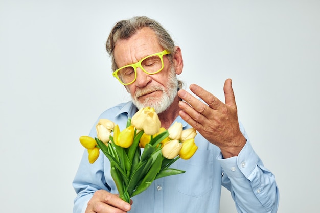 Stary człowiek bukiet kwiatów w okularach jako prezent jasne tło
