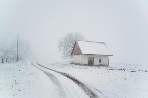 Stary dom na zimowym śnieżnym polu