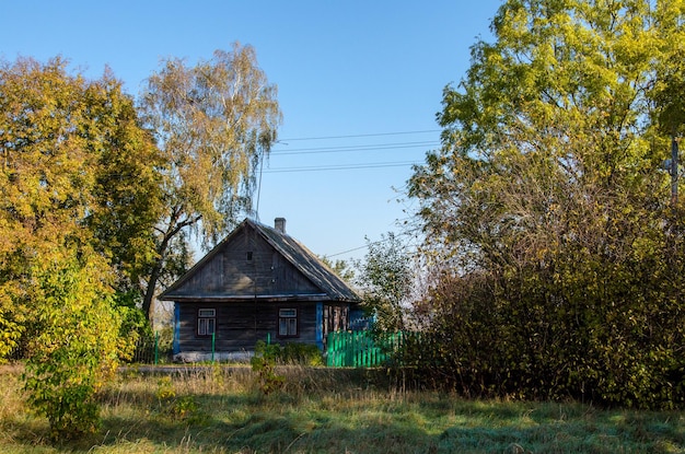 Stary drewniany dom na wsi otoczonej płotem i drzewami