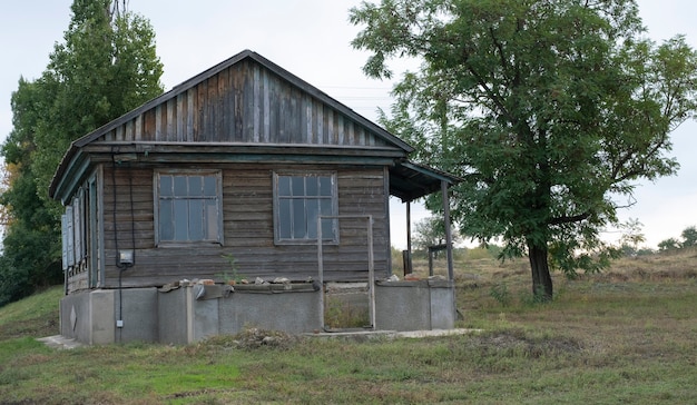 Zdjęcie stary drewniany opuszczony dom stojący samotnie na obrzeżach wsi.