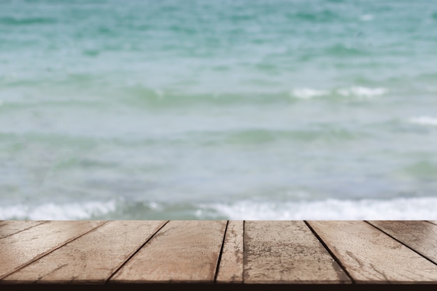 Stary drewniany stołowy wierzchołek na zamazanym plażowym tle, lata pojęcie