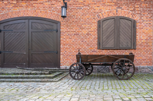 Stary Drewniany Wózek Pod Czerwonym Murem Z Bramami, Okiennicami I Latarnią