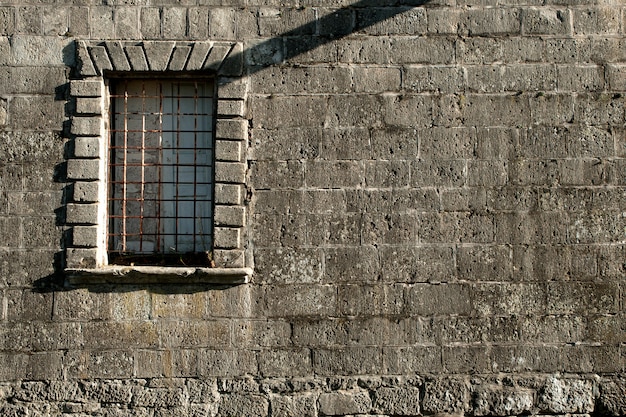 Stary kamienny mur z oknem i kratką