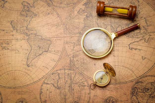 Zdjęcie stary kompas, szkło powiększające i piasek zegar na vintage mapę