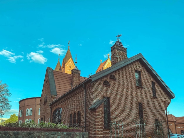 Stary kościół z czerwonej cegły w centrum miasta przecina małe kopułowe ściany z ogromnymi oknami sięgającymi od podłogi do sufitu