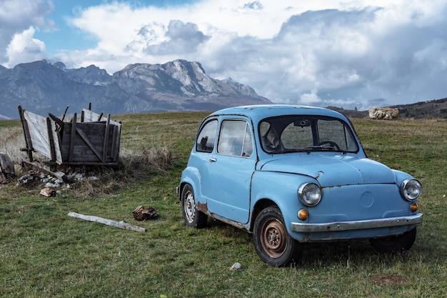 Stary niebieski samochód na tle pięknych gór Czarnogóry