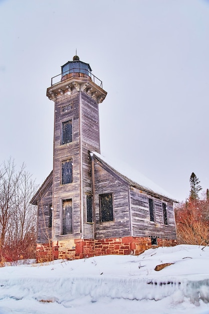 Stary opuszczony dom latarni zimą na wyspie podczas śniegu