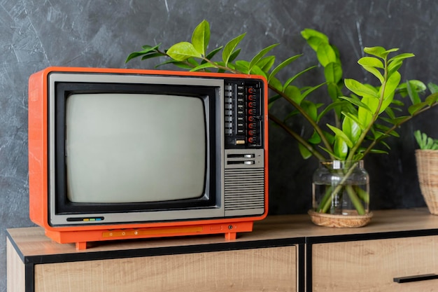 Stary pomarańczowy telewizor na drewnianej szafce w pokoju w domu Ściana na poddaszu Ciepła atmosfera