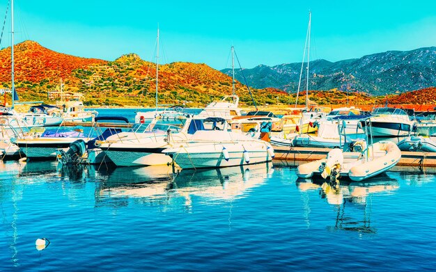 Stary port Sardynii i marina ze statkami na Morzu Śródziemnym w mieście Villasimius w południowej Sardynii we Włoszech w lecie. Pejzaż miejski z jachtami i łodziami