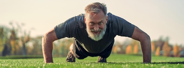 Zdjęcie stary sportowiec pchający się na trawie