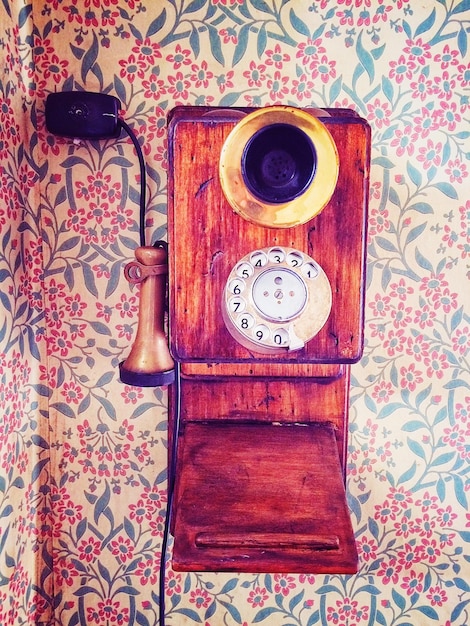 Zdjęcie stary telefon stacjonarny na ścianie z kwiatowym wzorem