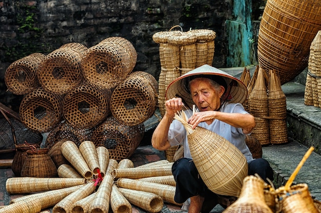 Stary Wietnamski żeński rzemieślnik robi tradycyjnemu bambusowi rybi oklepiec