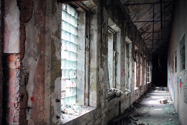 Zdjęcie stary zniszczony korytarz z odrapanymi ścianami i oknami