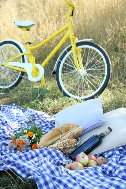 Zdjęcie stary żółty rower i przekąska piknikowa na kocu w kratkę na trawie w parku