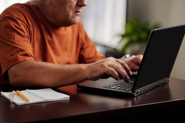 Starzejący się mężczyzna pracujący na laptopie