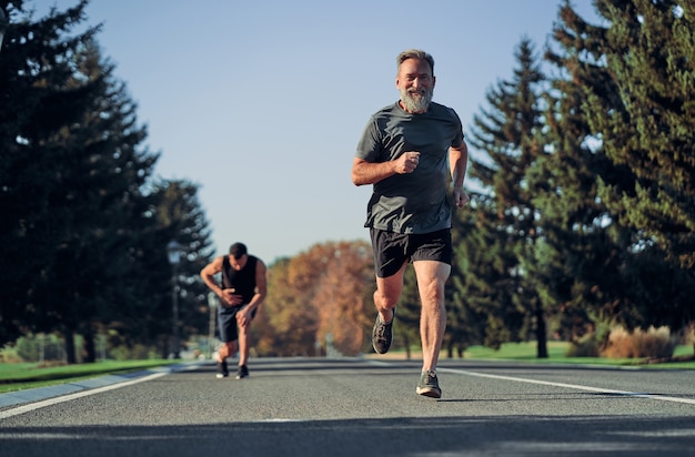 Starzy i młodzi sportowcy biegający po drodze