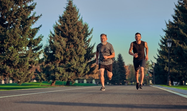 Starzy i młodzi sportowcy biegający po szosie