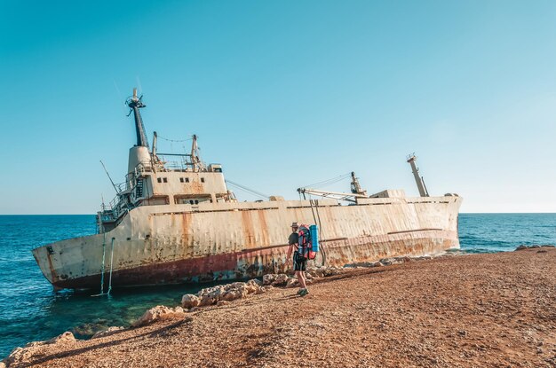 Statek widmo na plaży na Cyprze w pobliżu Pafos Turysta z plecakiem spaceruje wzdłuż plaży