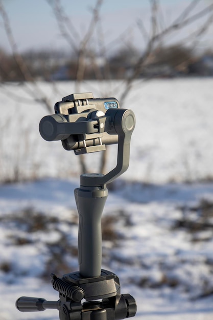 Steadicam do telefonu na statywie. Niewyraźne tło.