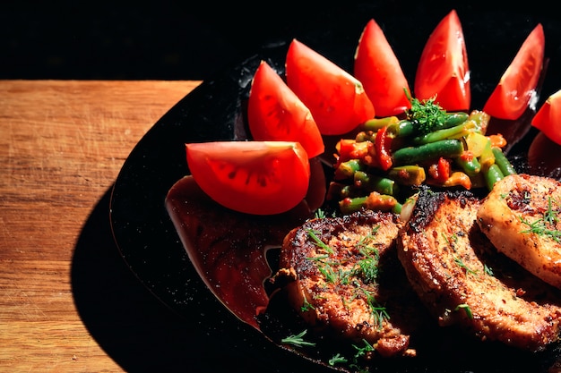 Stek wieprzowy na czarnym talerzu z warzywami