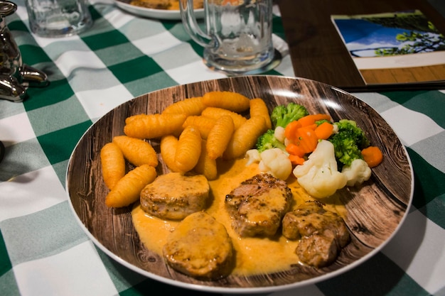 Stek wołowy i sos sosowy z gotowaną mieszanką warzyw i smażonym ziemniakiem na talerzu ceramicznym serwować obiad w restauracji w wiosce Pfunds w Tyrolu Austria