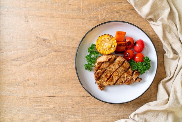 Zdjęcie stek z polędwicy wieprzowej z grilla i grilla z kukurydzą, marchewką i pomidorami