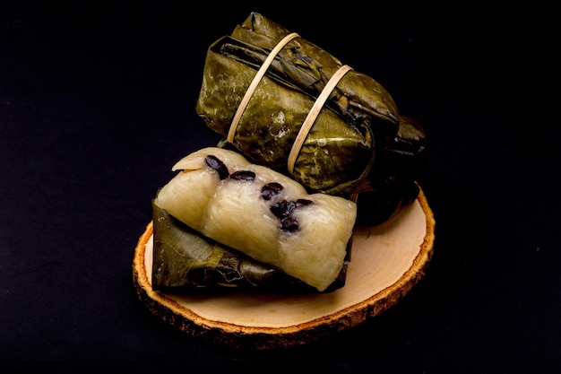 Sterta wiązanego ugotowanego ryżu jest ułożona na białym tle na czarnym tle Tajski deser z kleistego ryżu i mleka kokosowego nakłada nadzienie bananowe owinięte w liście bananowca i gotowane na parze do ugotowania